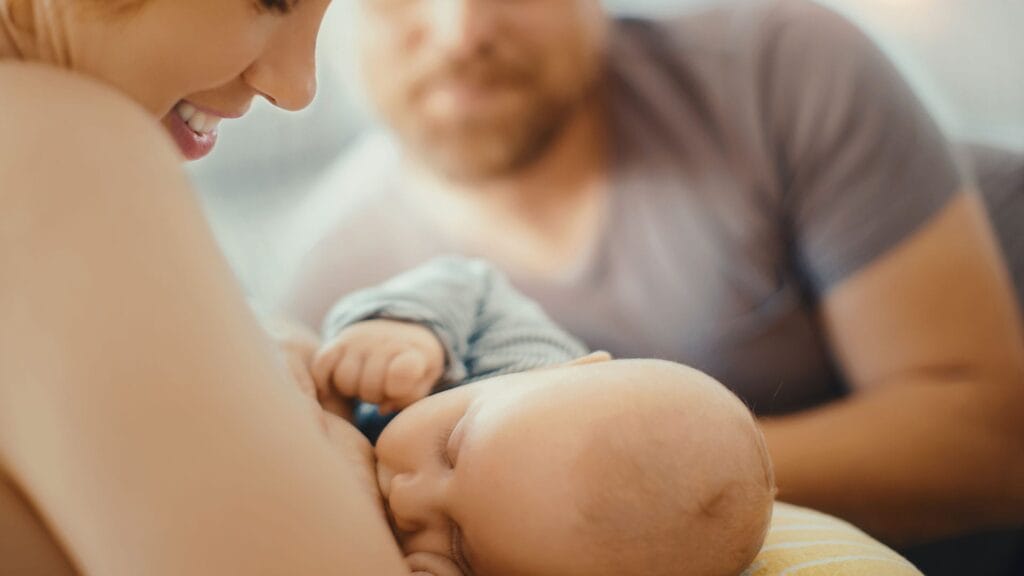 Ein Baby wird von einer Frau und einem Mann gestillt.